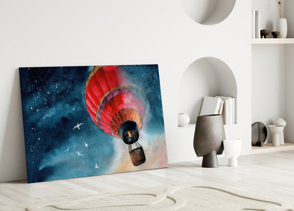 Red hot air balloon with basket ascending toward starry night sky, leaning against white wall in minimalist room setting.
