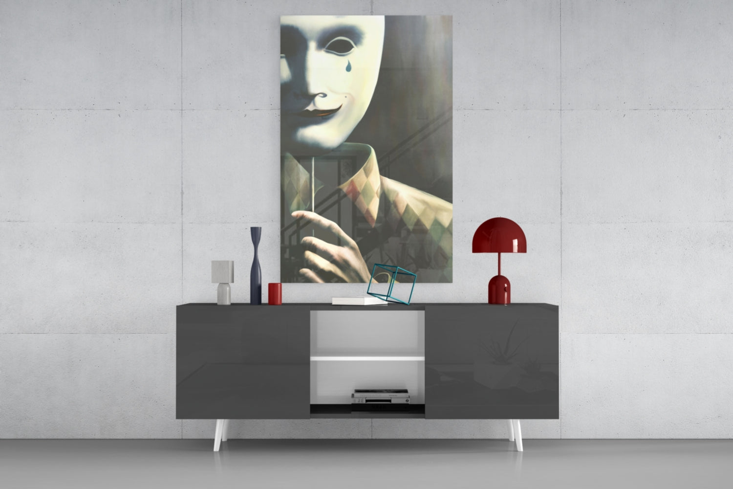 Glass wall art depicting a masked face with teardrop detail displayed above a dark console table with decorative items.