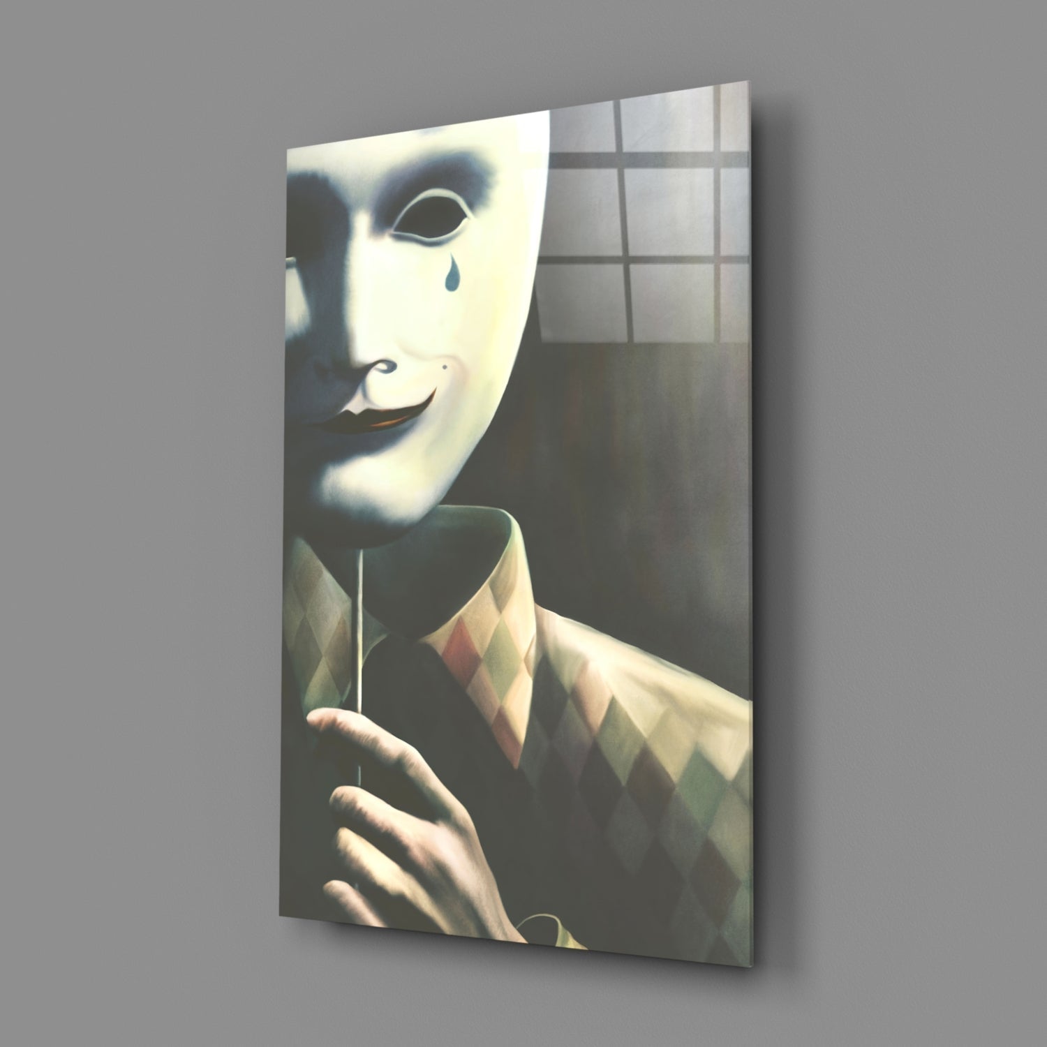 A figure wearing a white theatrical mask with a tear drop and a patterned jacket displayed on glass wall art, angled perspective showing depth and shadow.