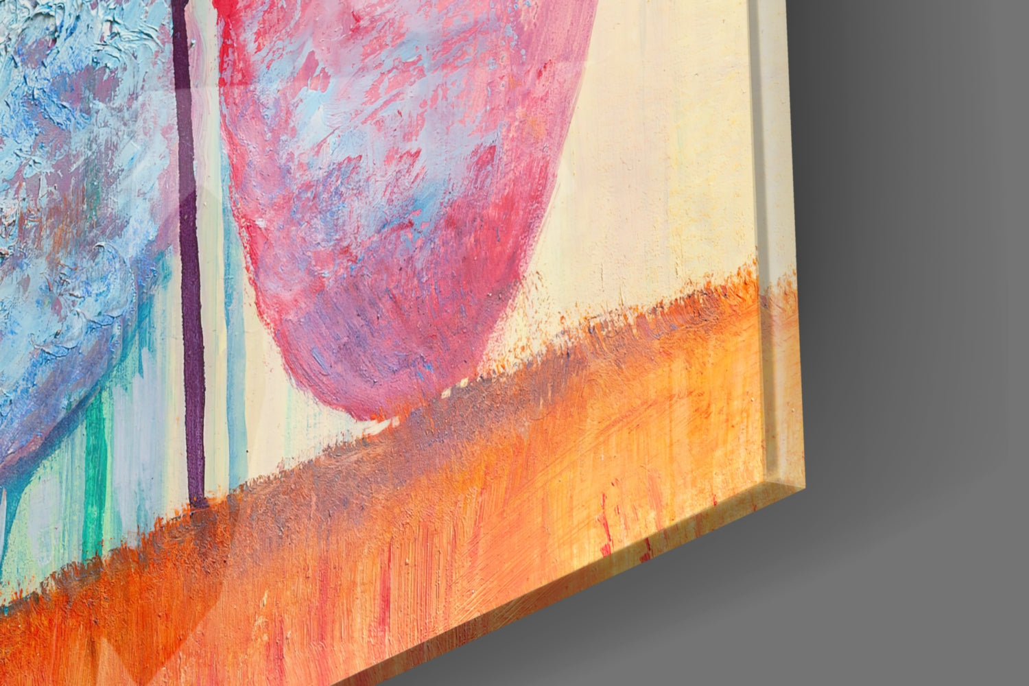 Close-up angled view of colorful abstract glass art featuring pink, orange, blue, and green brushstrokes with visible texture and wooden edge.