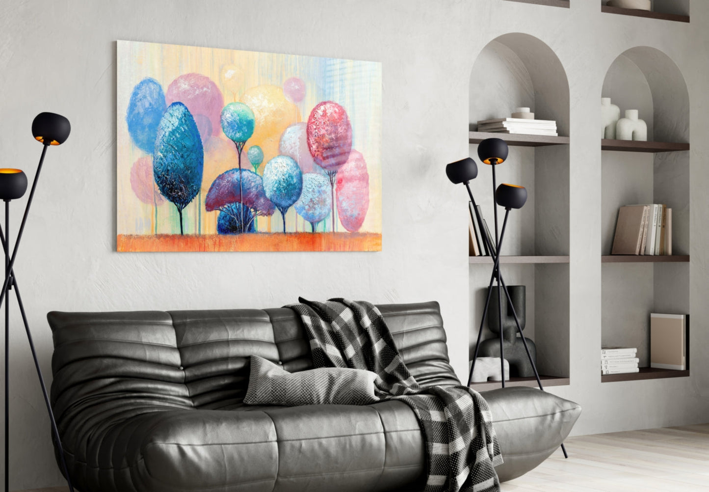 Colorful glass wall art depicting blue, pink, and yellow trees displayed above a black leather sofa in a modern living room.
