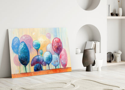 Colorful glass wall art depicting blue, pink, and red trees leaning against white interior wall with ceramic vessels and shelving.