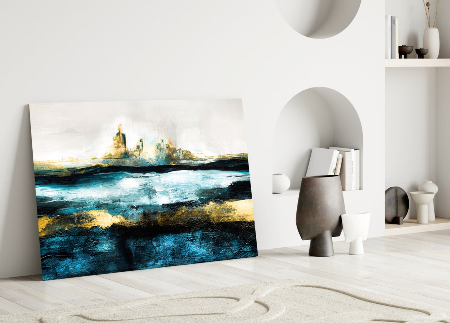 Glass wall art leaning against white wall displays coastal landscape with turquoise ocean, golden cliffs, and castle ruins.