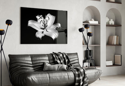 Black and white lily glass wall art displayed above a gray leather sofa in a modern living room interior.