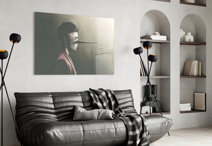 Liar Glass Wall Art depicting a man in profile with elongated nose, displayed above black leather sofa in modern living room interior.