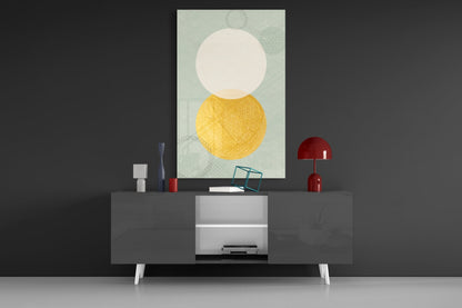 Sun and Moon glass wall art displayed above a dark media console, showing cream circle atop yellow circle on pale green patterned background.