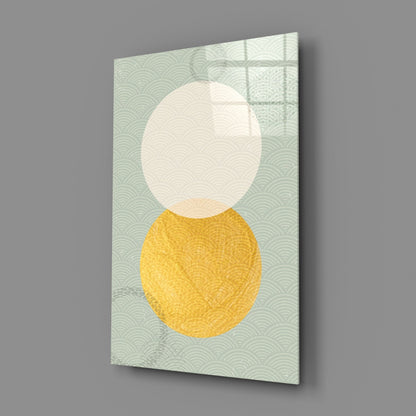 Angled view of glass wall art featuring cream and yellow circles on pale green patterned background.