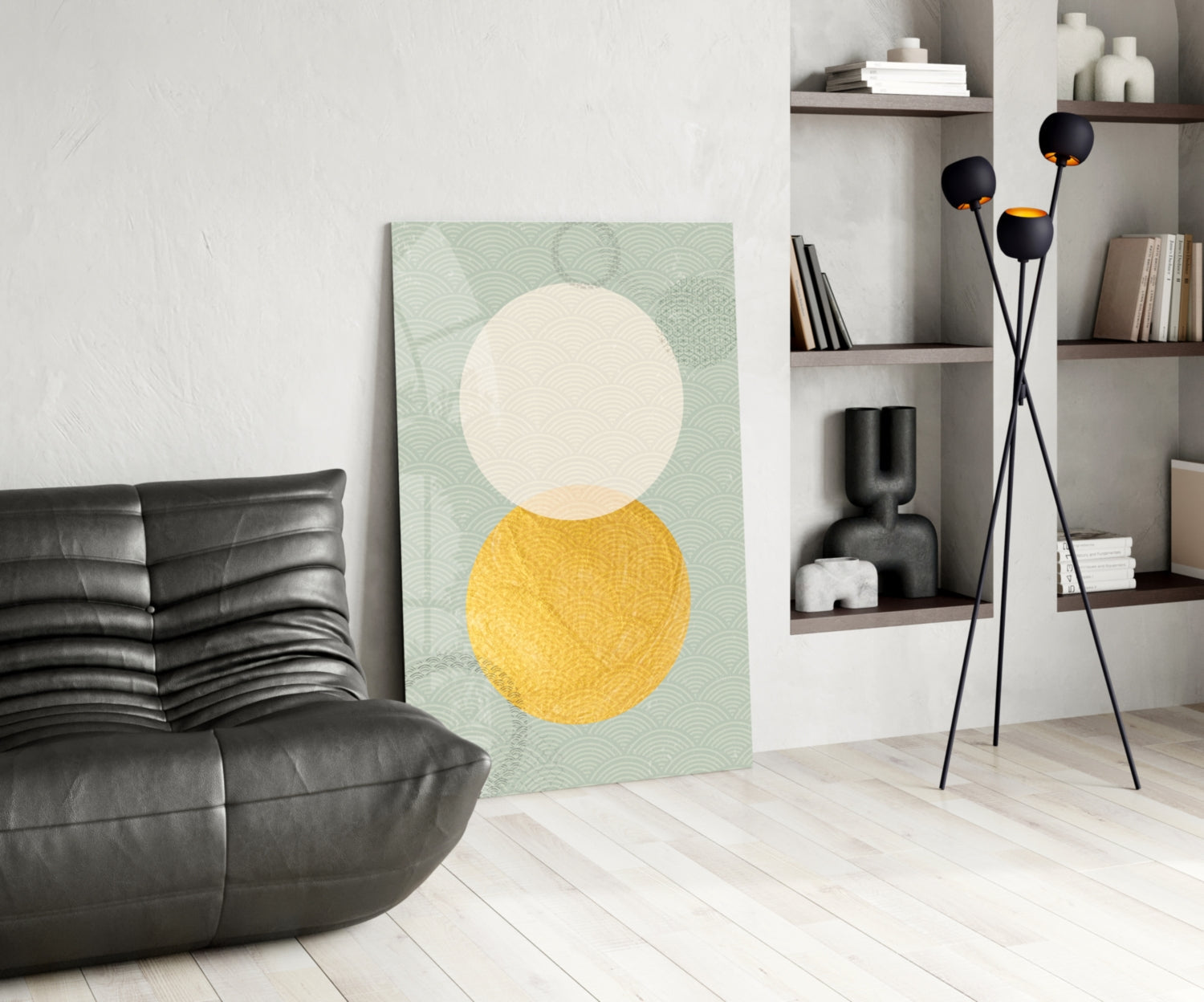 Sun and Moon Glass Wall Art displayed against white wall in modern living room with black leather chair and shelving unit.