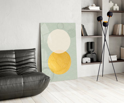 Sun and Moon Glass Wall Art displayed against white wall in modern living room with black leather chair and shelving unit.