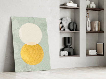 Modern living room interior with geometric glass wall art leaning against white wall beside wooden shelving units displaying decorative objects and books.