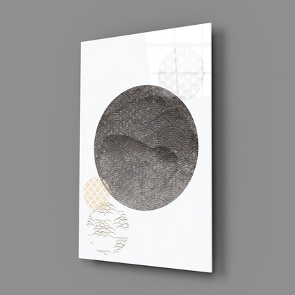 Angled perspective view of Black Moon Glass Wall Art displaying a large dark circular pattern with smaller geometric designs in corners on white background.