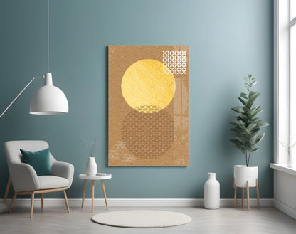 Framed glass wall art featuring a large yellow circle against tan geometric patterned background, displayed in modern living room interior.
