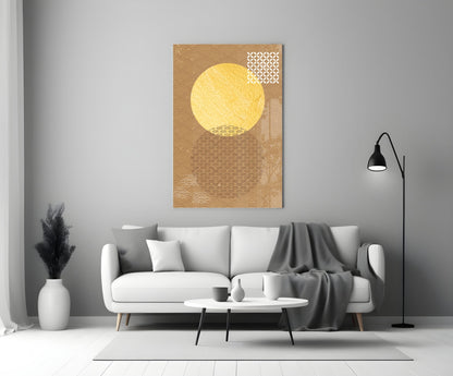 Gold-toned glass wall art with a large yellow circular sun and geometric patterns displayed above a white sofa in a modern living room.