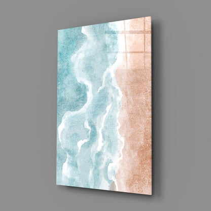 Angled view of glass wall art showing turquoise ocean waves and sandy beach in cream and peach tones.