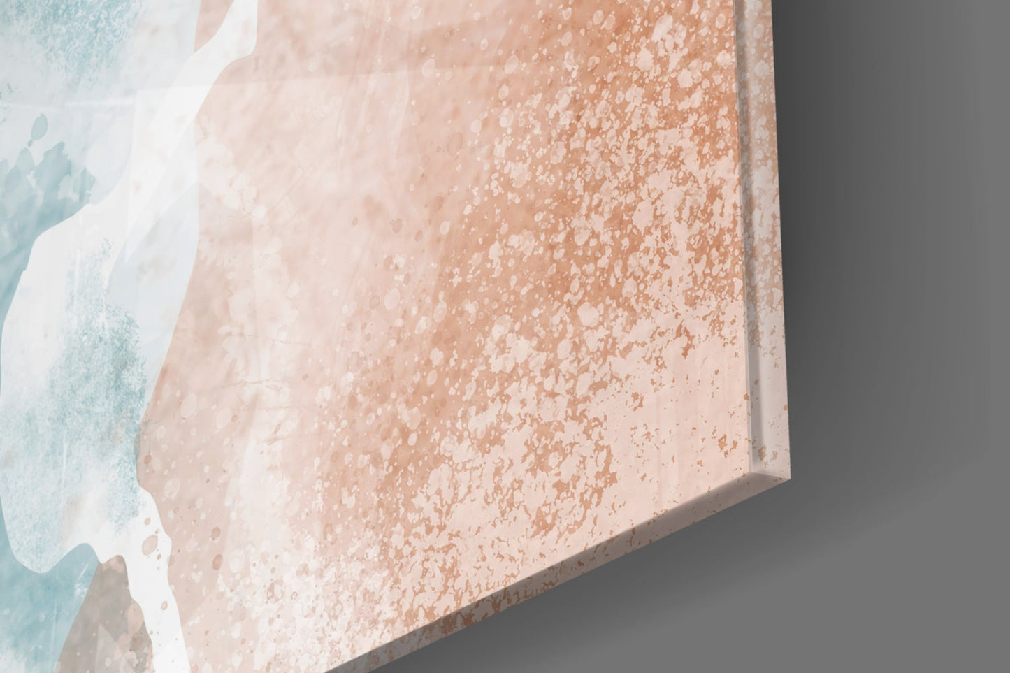 Close-up angled view of textured beach glass wall art showing peachy-beige speckled surface with white and turquoise watercolor edges.
