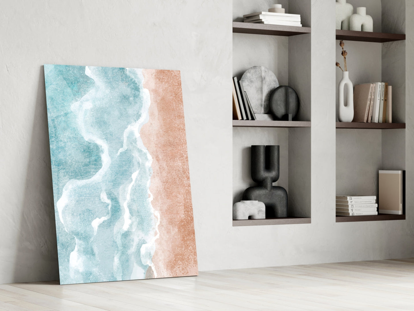 Beach glass wall art leaning against white wall beside open shelving displaying books, vases, and decorative objects.
