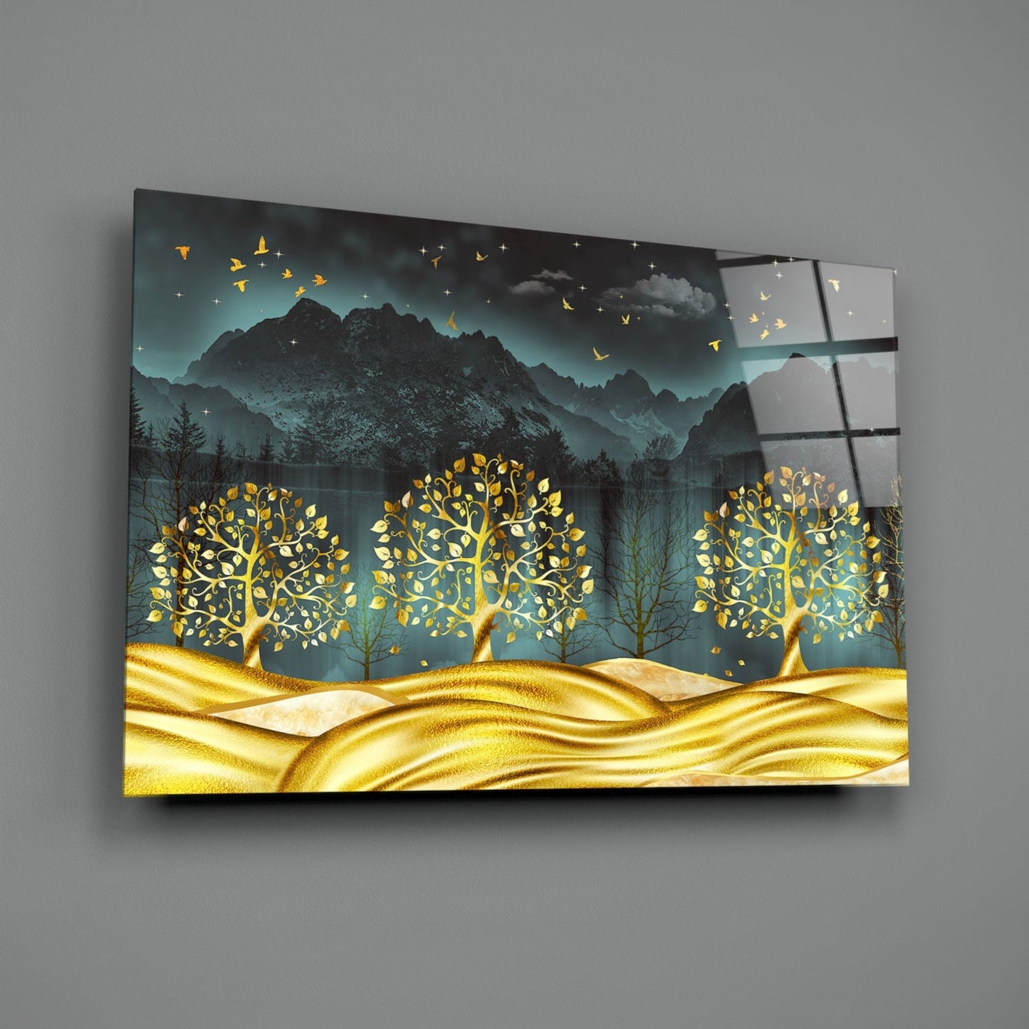 Golden Forest Glass Wall Art displayed at an angle, showing three glowing gold trees against mountains and teal sky with flying birds.
