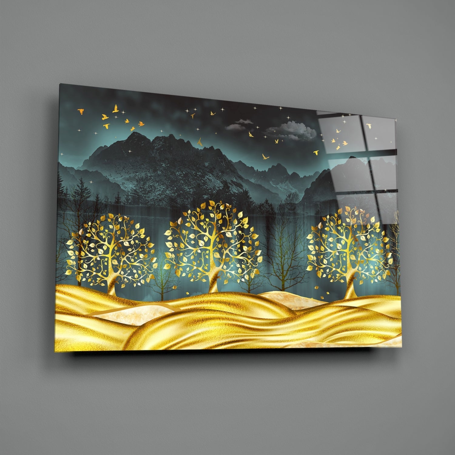 Golden Forest Glass Wall Art displayed at an angle, showing three glowing gold trees against mountains and teal sky with flying birds.