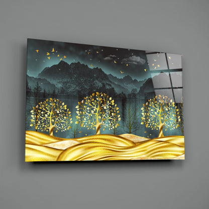 Golden Forest Glass Wall Art displayed at an angle, showing three glowing gold trees against mountains and teal sky with flying birds.