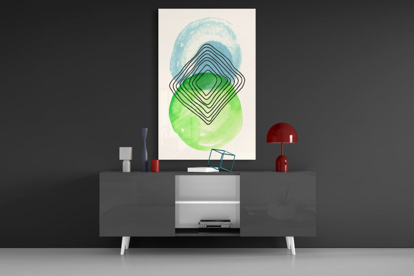 Abstract glass wall art with concentric blue and green geometric shapes displayed above a modern gray media console in a styled interior setting.