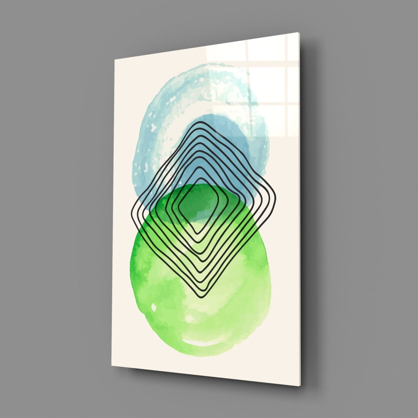 Glass wall art panel displayed at an angle showing blue and green watercolor shapes with overlapping black line geometric patterns on cream background.