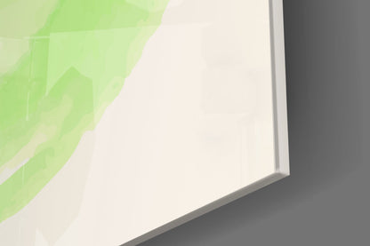 Close-up angled view of glass wall art with green geometric shapes and white negative space against gray background.