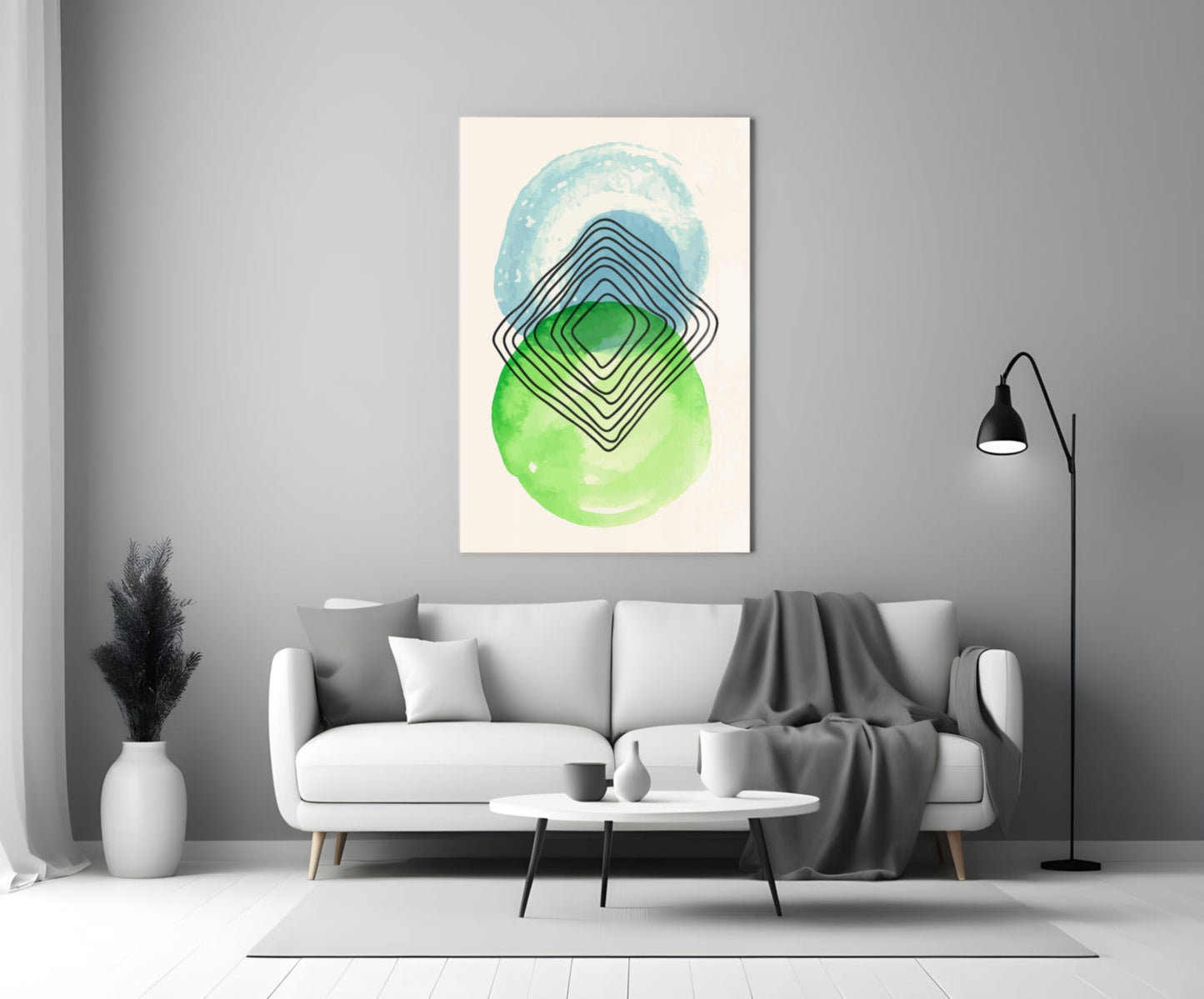 Abstract wall art with concentric diamond shapes in blue, green, and black on cream background, displayed above a white sofa in a modern living room.