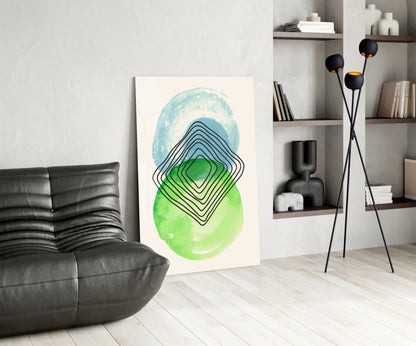 Modern living room interior featuring abstract glass wall art with blue and green watercolor ovals and black concentric line patterns displayed leaning against white wall.