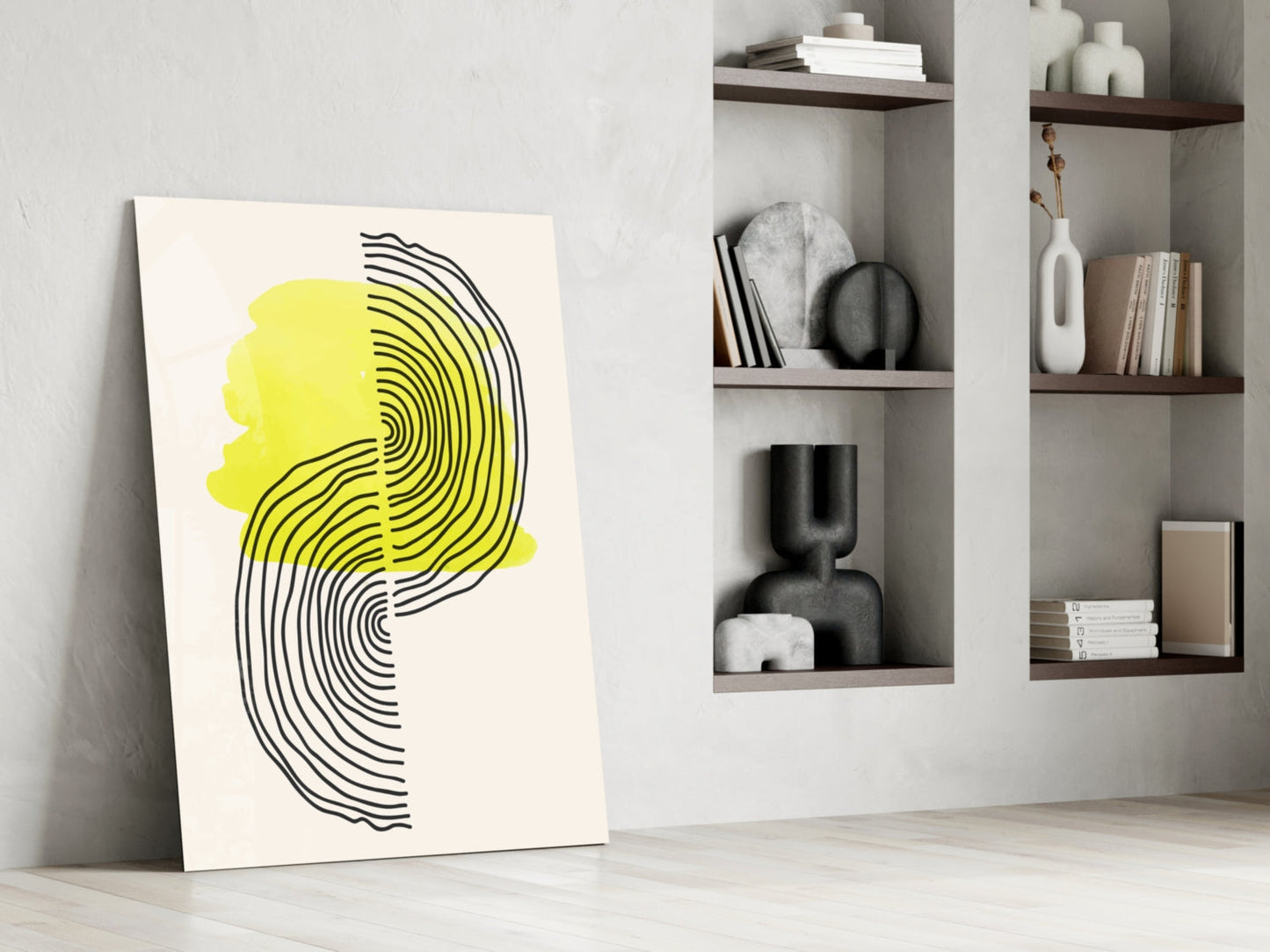 Modern abstract wall art leaning against white wall featuring yellow and black concentric line profile design next to shelving unit.