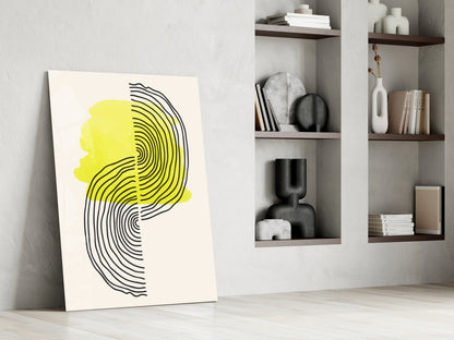 Modern abstract wall art leaning against white wall featuring yellow and black concentric line profile design next to shelving unit.