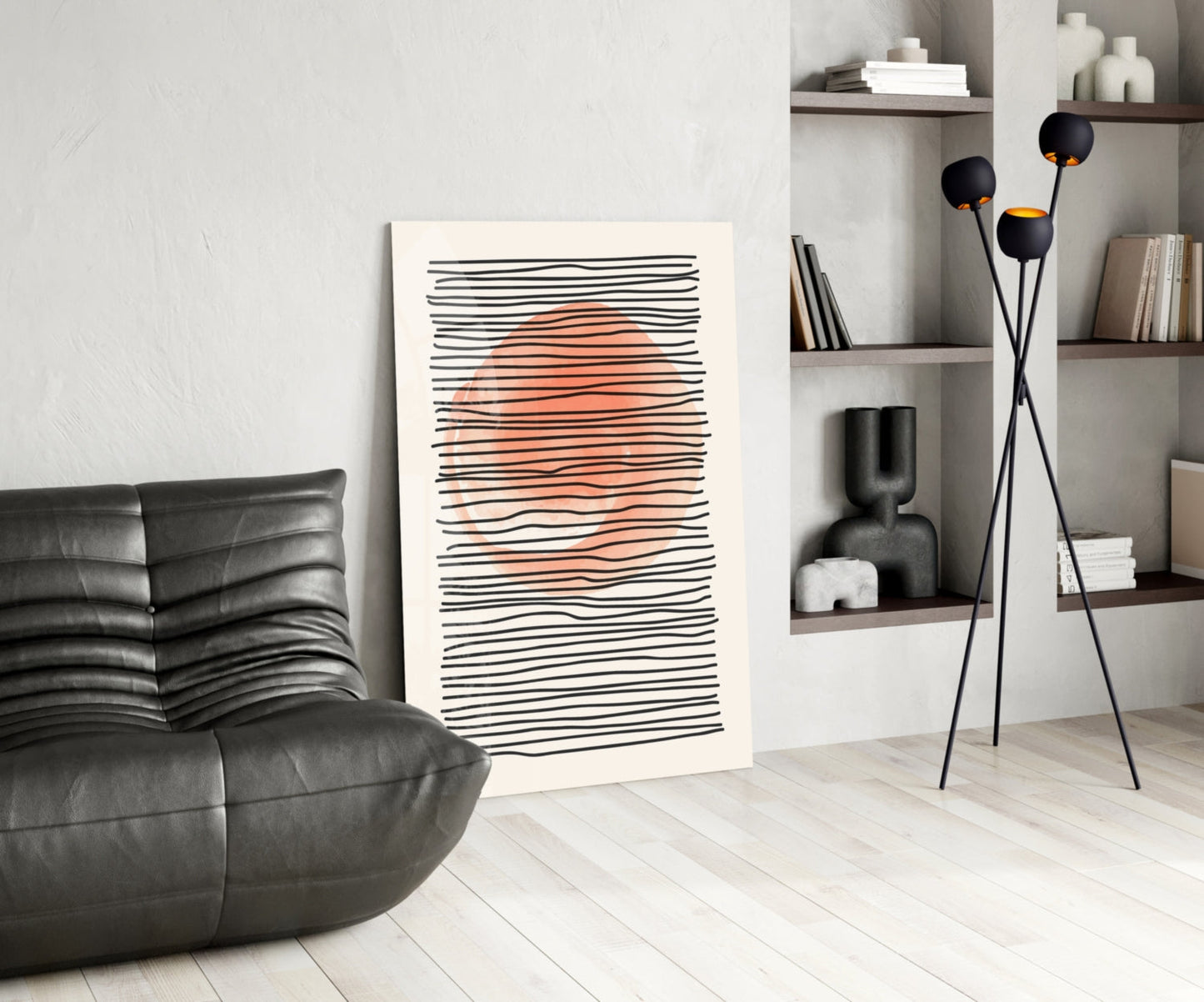 Modern living room interior featuring abstract wall art with black horizontal lines and coral orange center, displayed next to black leather furniture and tall floor lamp.