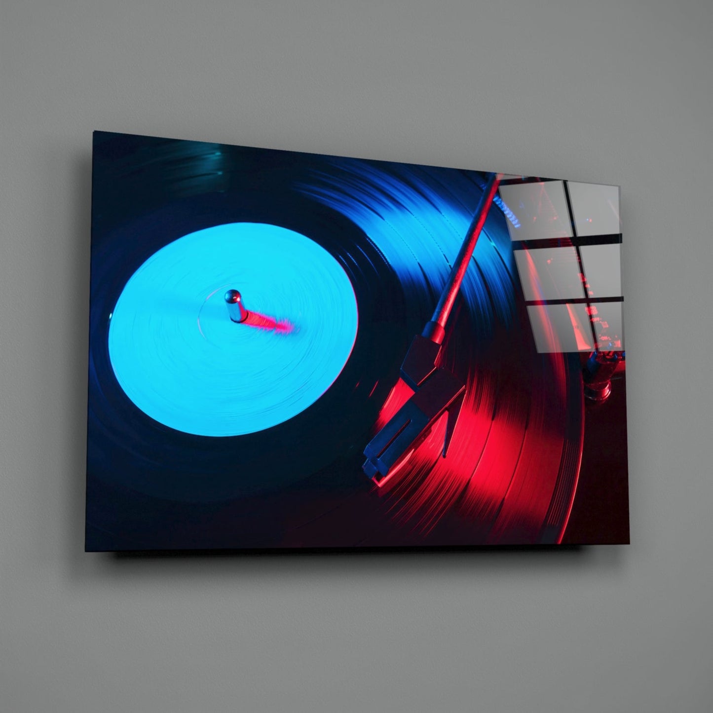 Angled view of glass wall art displaying neon-lit turntable with cyan vinyl record and red tonearm against dark background.