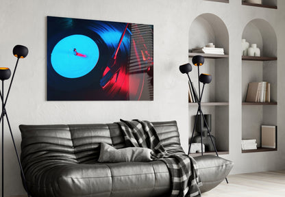 Modern living room with neon gramophone glass wall art displaying cyan circle and red vinyl record above gray leather sofa.