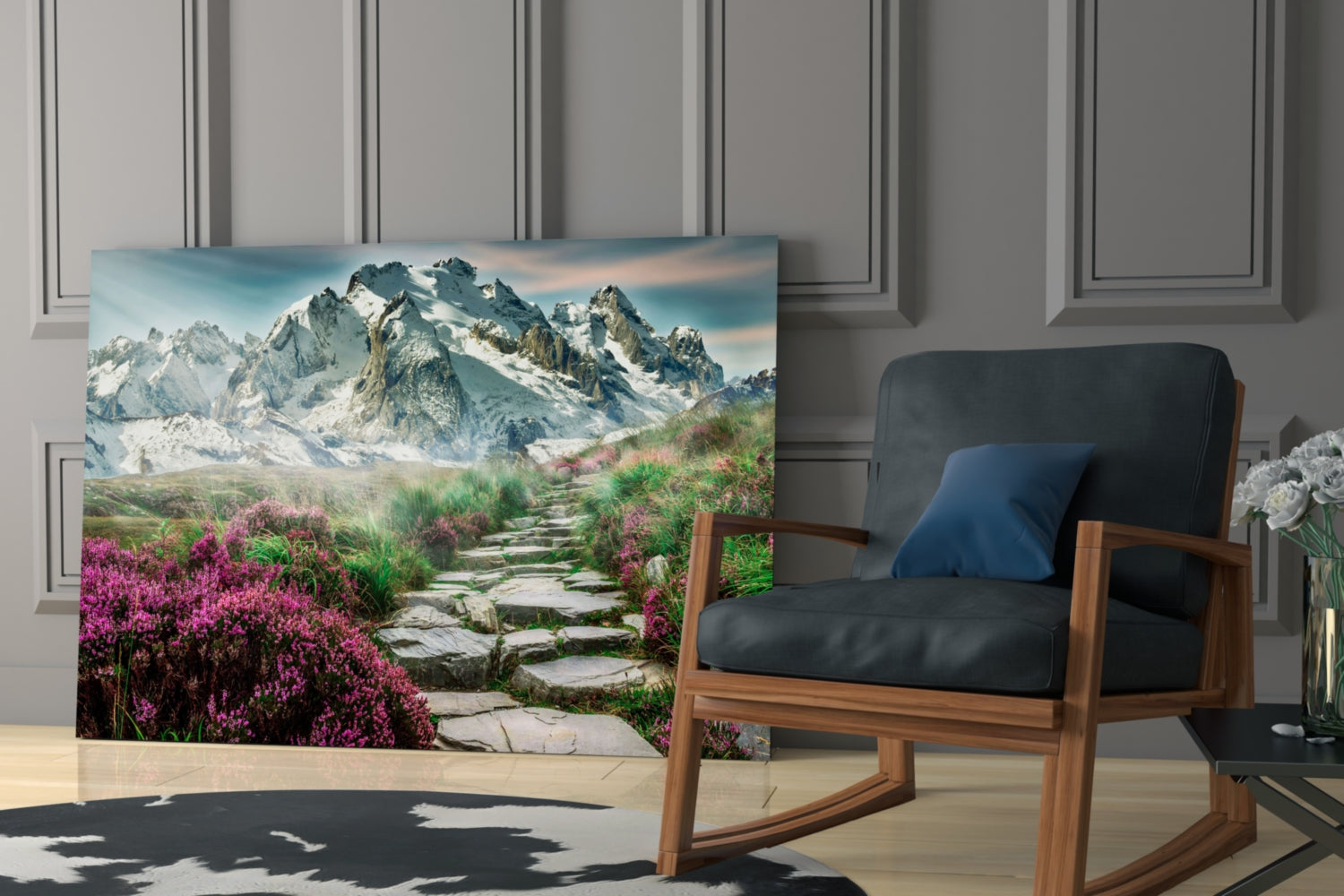 Glass wall art displaying a mountain landscape with purple wildflowers and stone pathway, displayed in a modern living room setting next to a wooden chair.