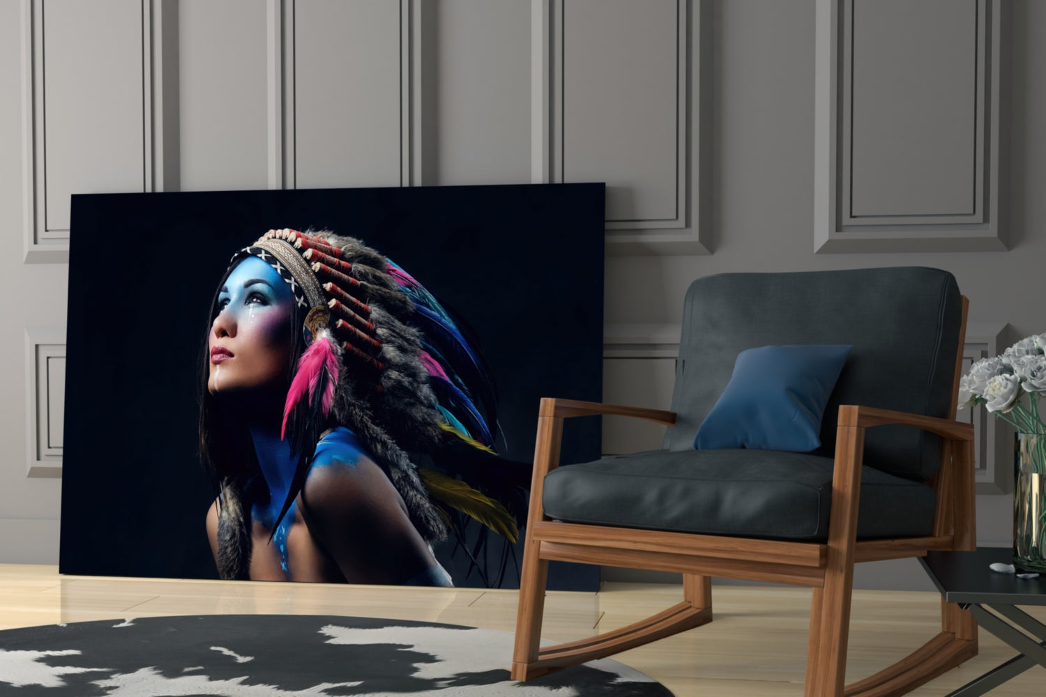 Glass wall art displaying a woman with blue face paint and colorful feathered headdress against black background, displayed in modern living room setting.