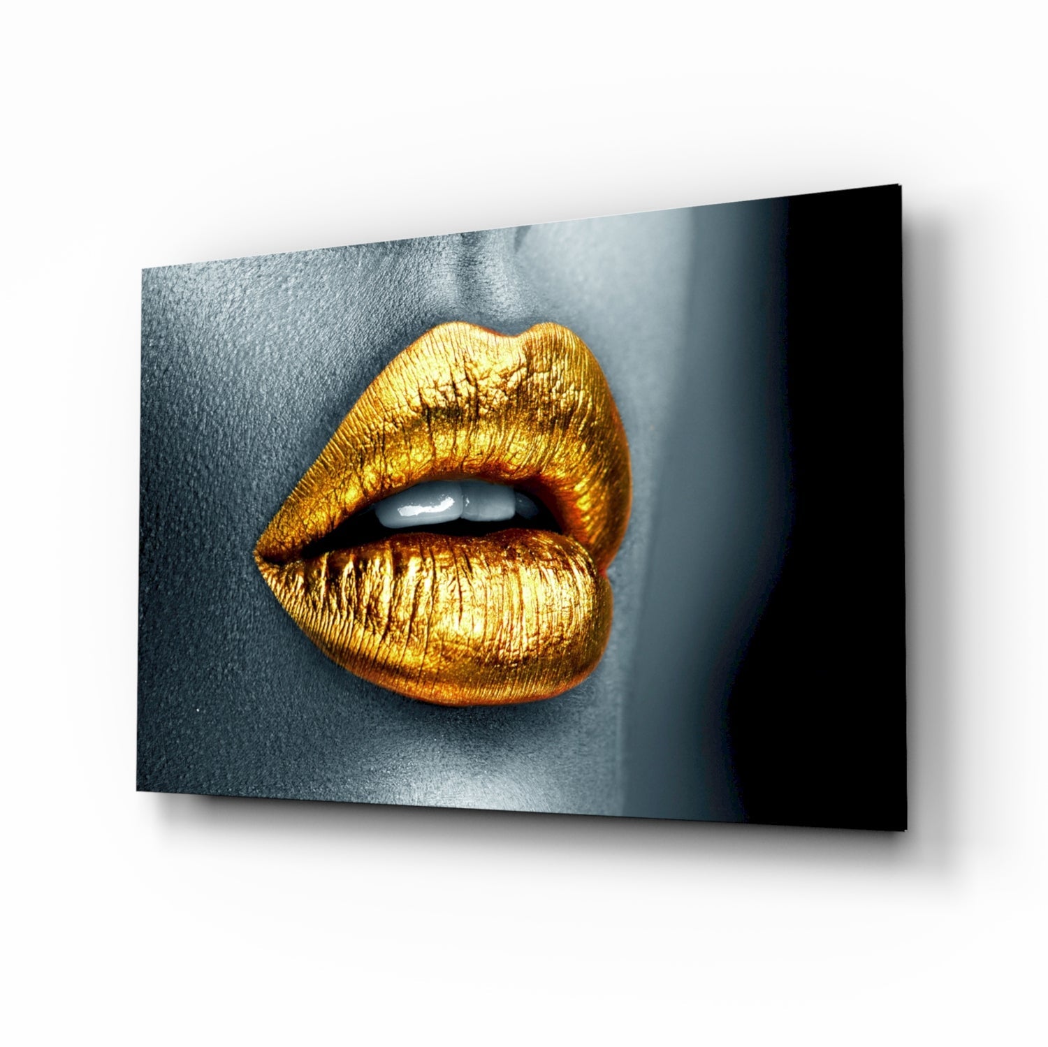 Angled perspective view of a glass wall art panel featuring golden metallic lips against a dark blue-grey textured background.