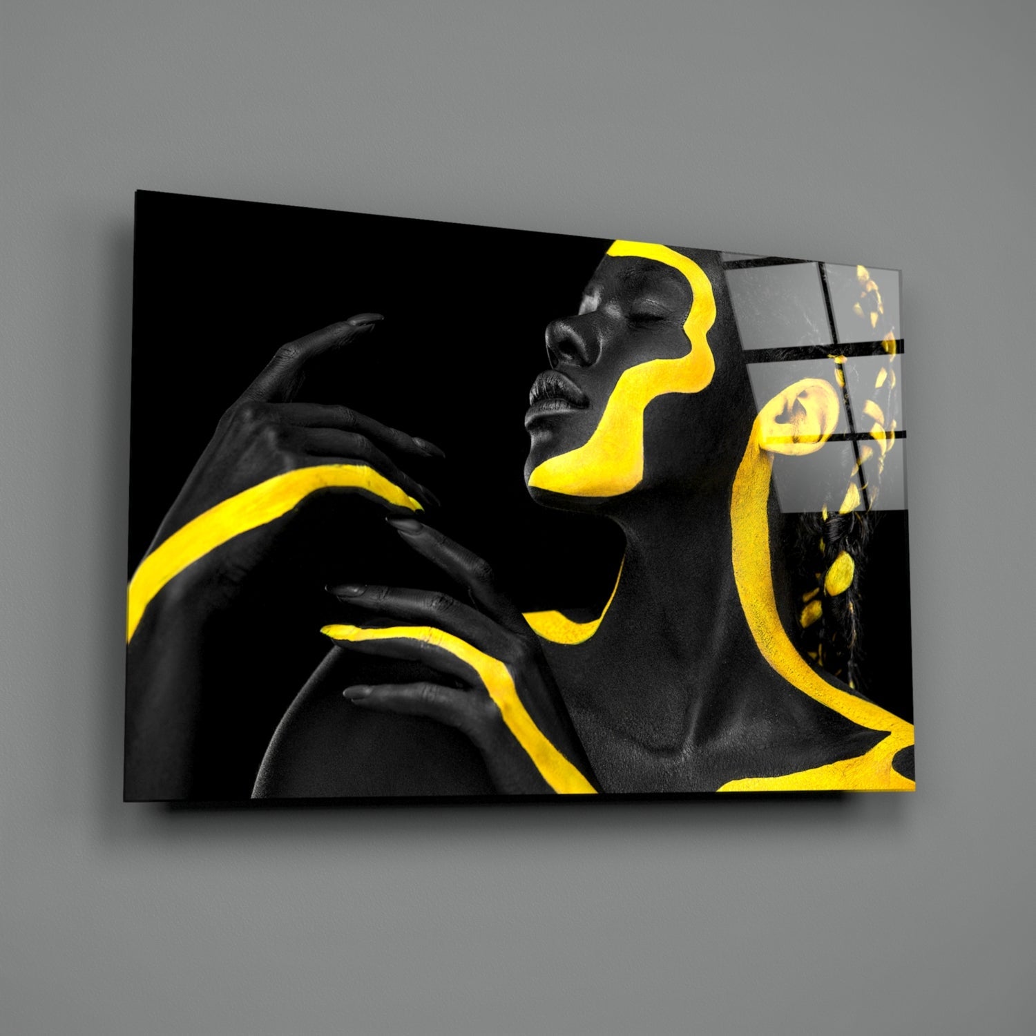 Black and yellow glass wall art displaying a profile silhouette with neon yellow facial features and flowing design elements against gray background.