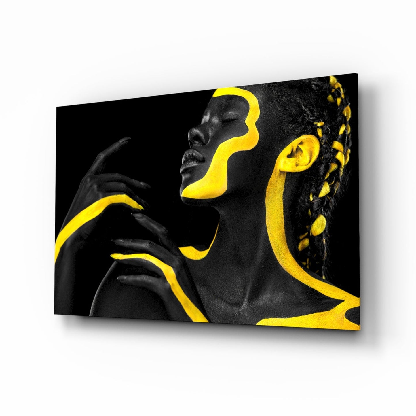 Angled view of glass wall art featuring a woman's profile with black and yellow geometric paint design on dark background.