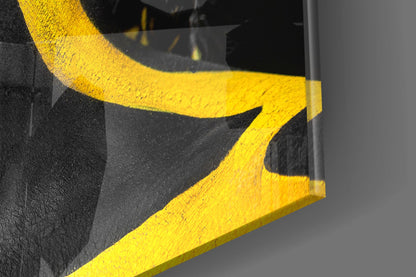 Close-up detail of yellow painted glass showing curved brushstrokes against dark textured background.