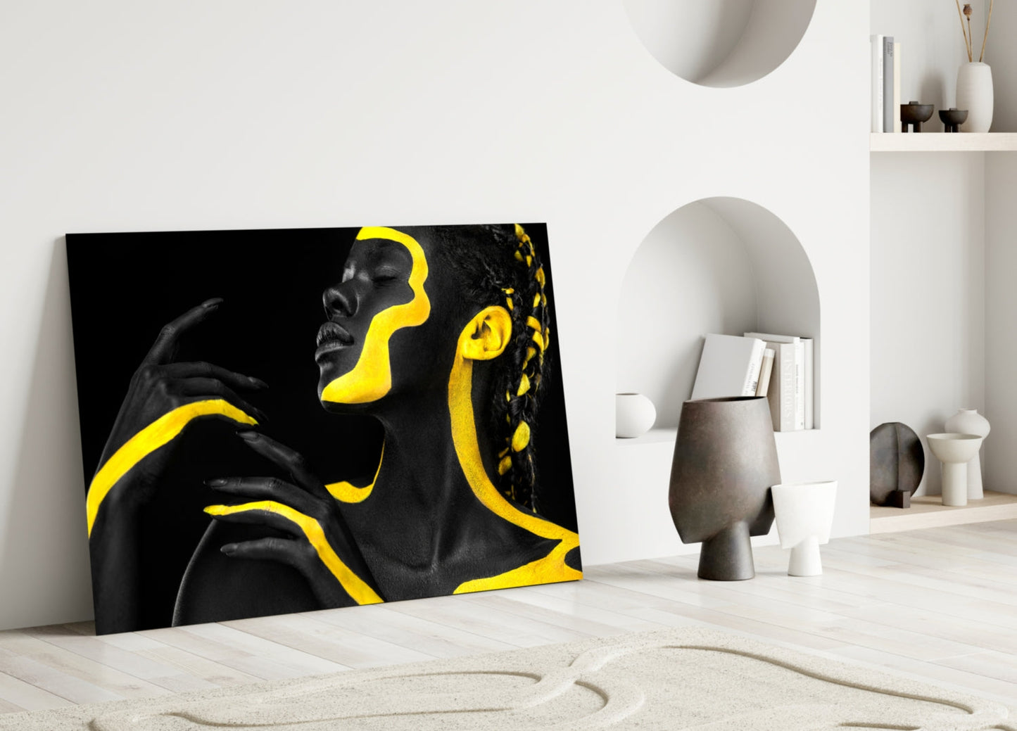 Black and yellow glass wall art leaning against white wall in minimalist interior with decorative objects.