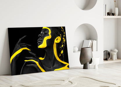 Black and yellow glass wall art leaning against white wall in minimalist interior with decorative objects.