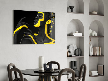 Black and yellow glass wall art depicting a woman's profile displayed above a round dining table in a modern interior.