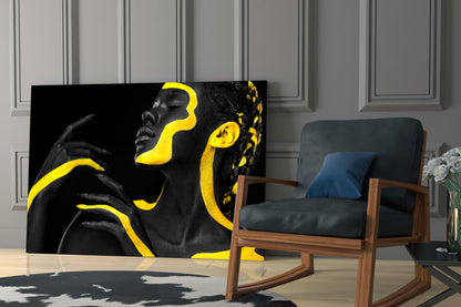 Yellow Woman Glass Wall Art displayed on a living room wall beside a wooden chair with black cushions.