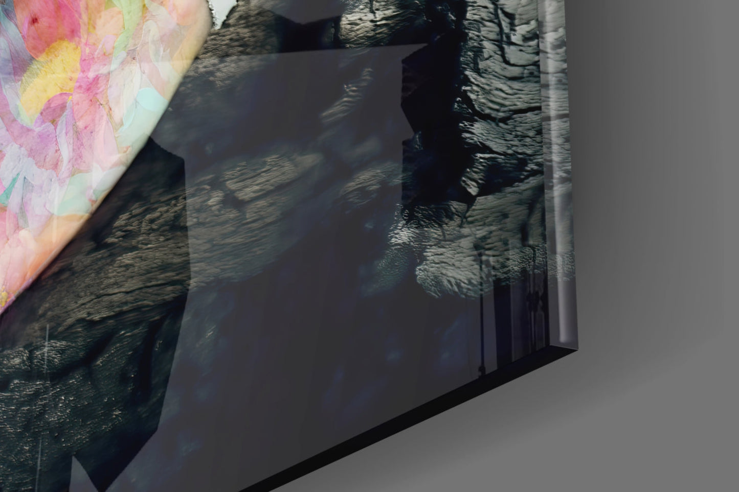 Close-up angled view of glass wall art displaying textured dark tree bark imagery with pink and yellow floral design in upper left corner.