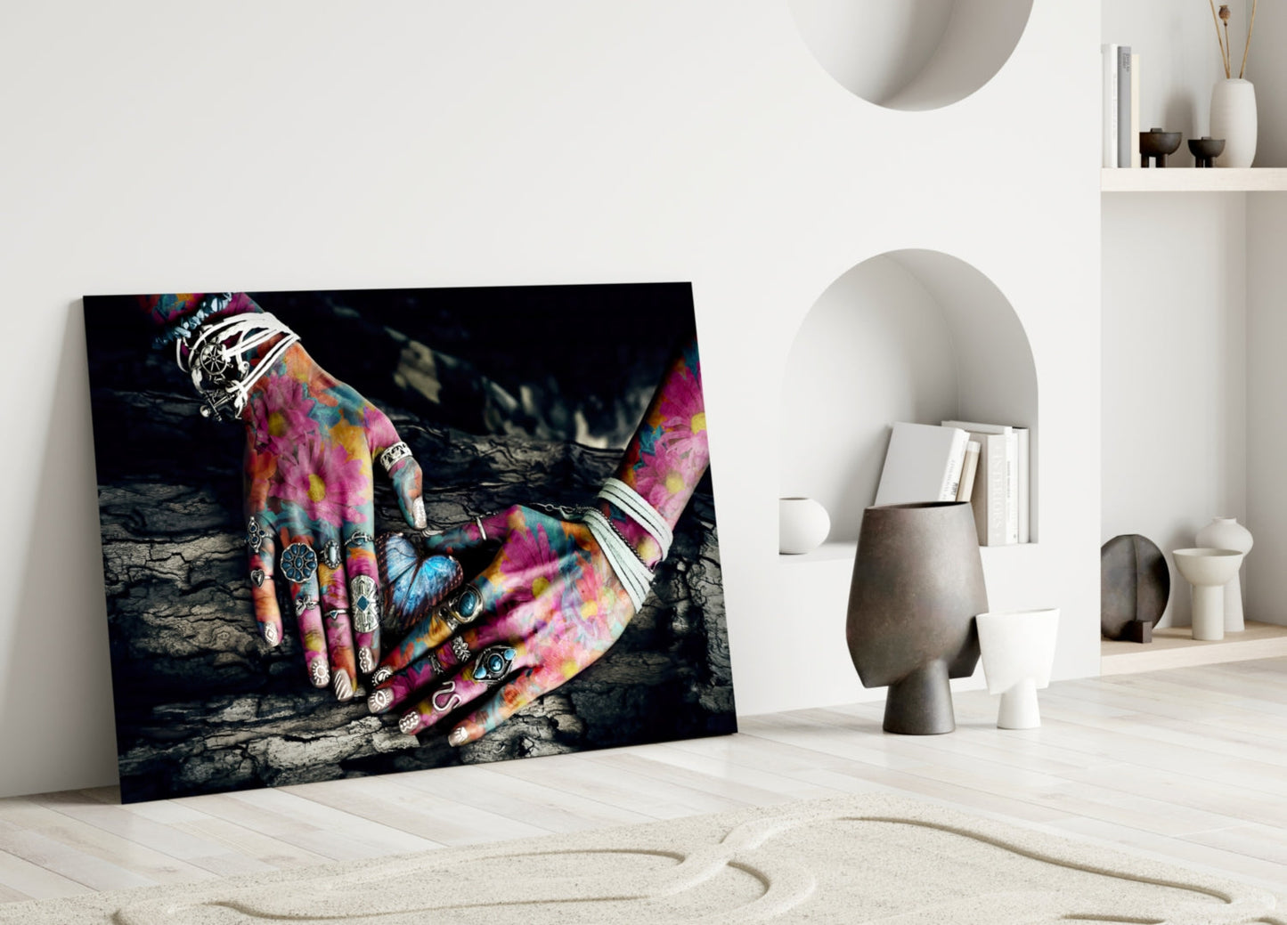 Vibrant glass wall art displaying colorful tattooed hands leaning against textured dark background, displayed in minimalist white interior setting.