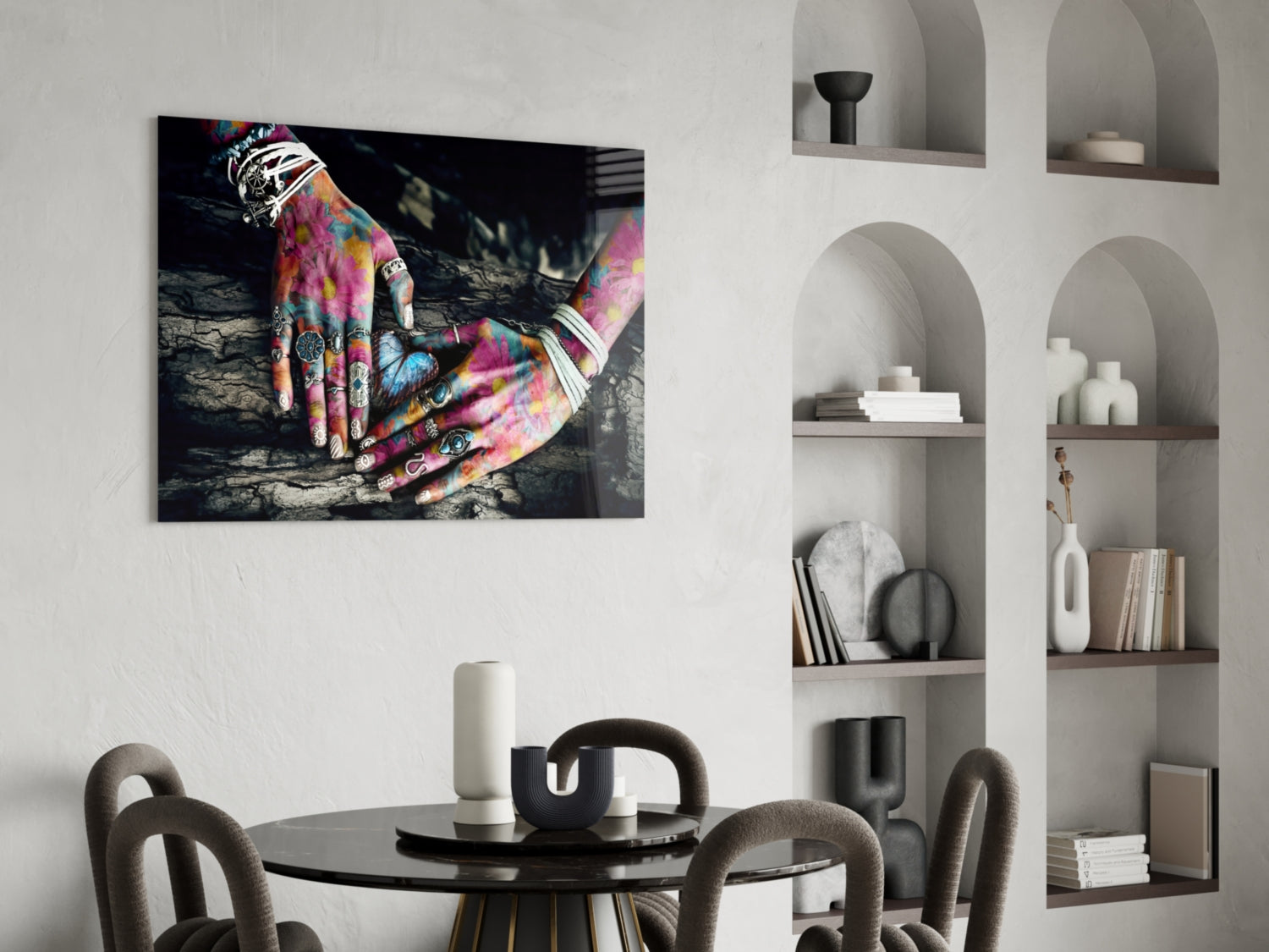 Colorful tattooed hands resting on dark wood displayed as glass wall art above a dining table in modern interior setting.
