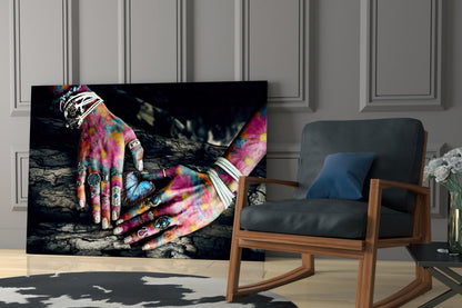 Glass wall art displaying vibrant multicolored tattooed hands on textured dark background, displayed in modern living room setting.