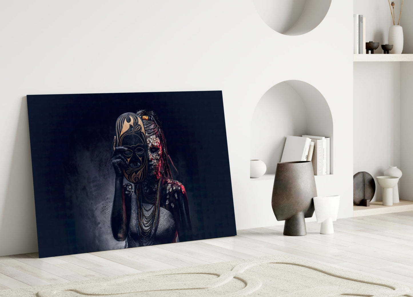 Glass wall art leaning against white wall displays figure with ornate black mask and red fabric on dark blue background.