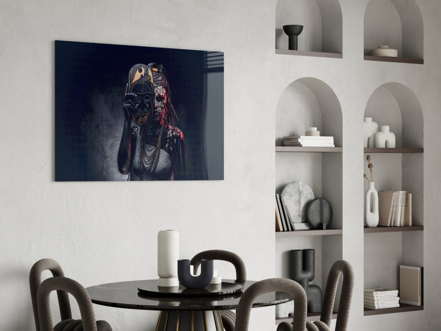 Dark blue glass wall art depicting an ornate masked figure with gold and red details, hung above a black dining table in a modern interior.
