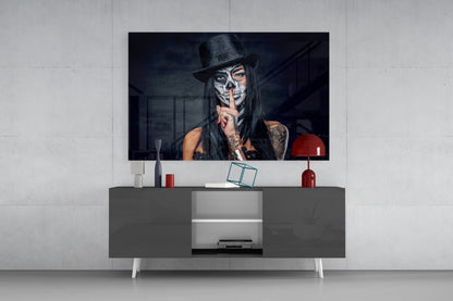 Modern media console with gray storage cabinet displaying glass wall art of woman with skull makeup and black hat above.